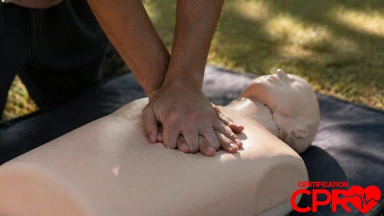 Person performing hands-only CPR on a mannequin outdoors in Tallahassee.